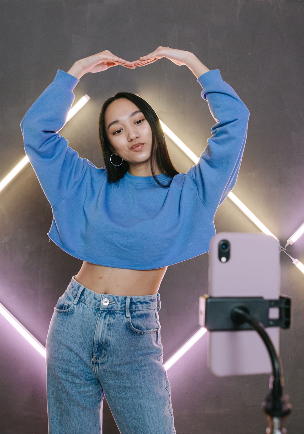 Ung influencer filmar sig själv med mobil framför neonljus