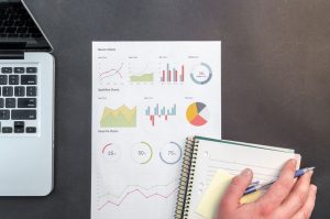Skrivbord med rapportdiagram och en laptop ovanifrån