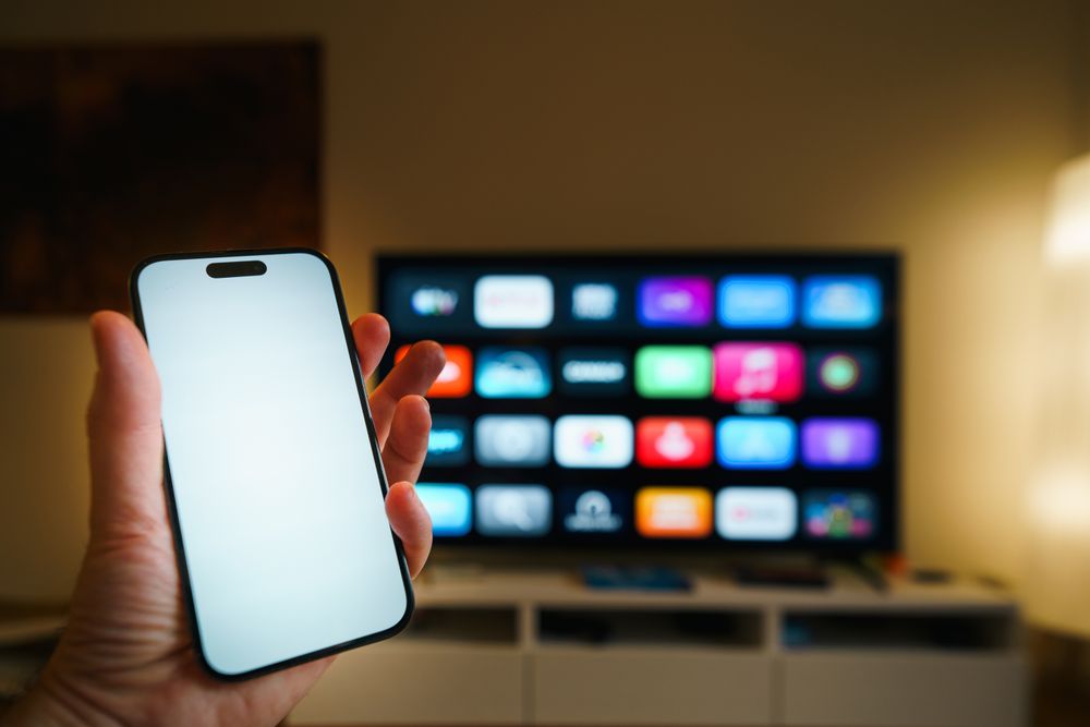Smart-tv med streamingappar i ett vardagsrum, mobil i förgrunden