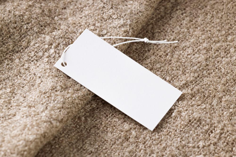 Närbild på en blank prislapp mot beige tyg