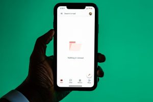 Hand håller en smartphone som visar en e-postapp