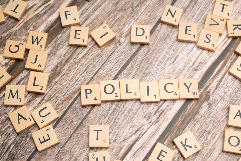 Bokstavsbrickor som bildar ordet Policy på träbakgrund