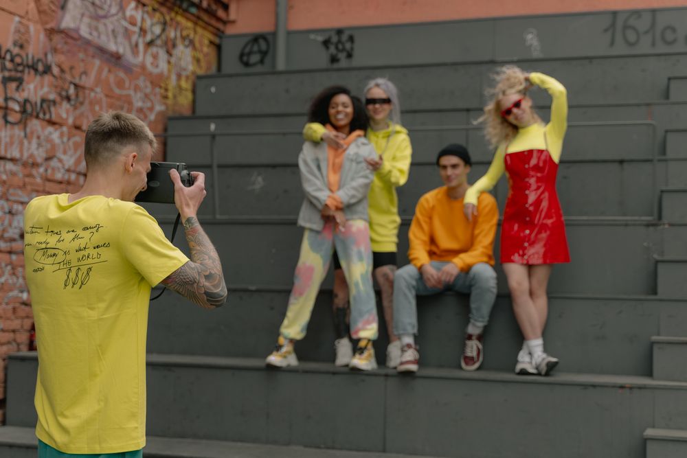 Grupp vänner poserar för en modefotografering mot en graffitivägg