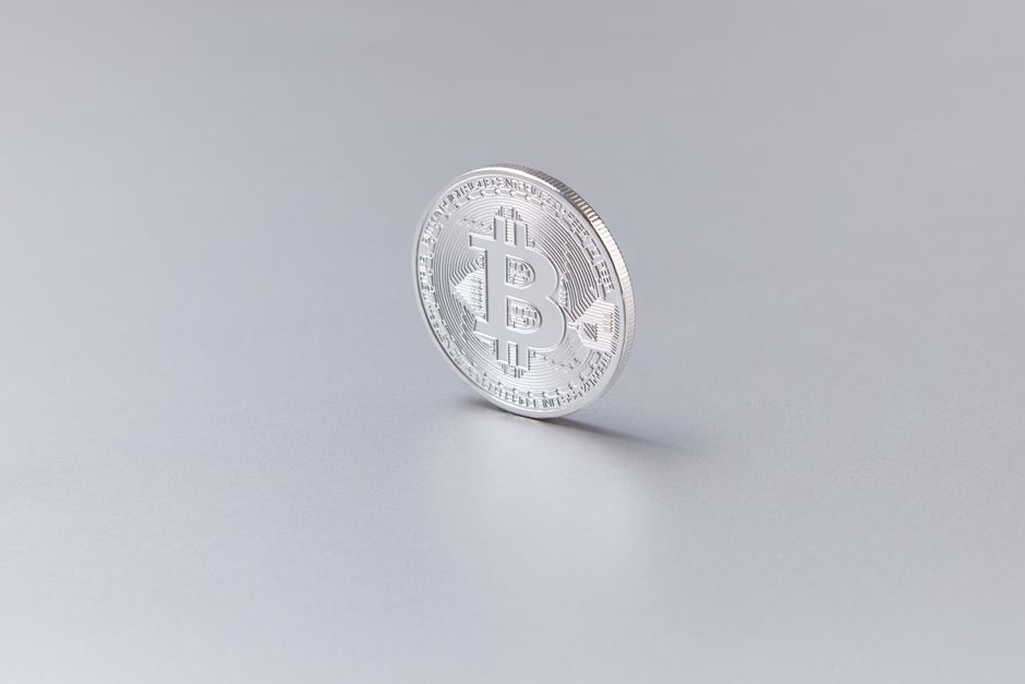 Närbild på ett silverfärgat bitcoin-mynt mot vit bakgrund