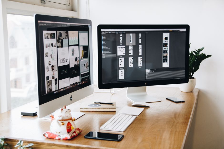 Arbetsplats med två skärmar som visar designprogram