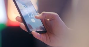 Närbild på en hand som håller en mobiltelefon låst med fingeravtryckssensor