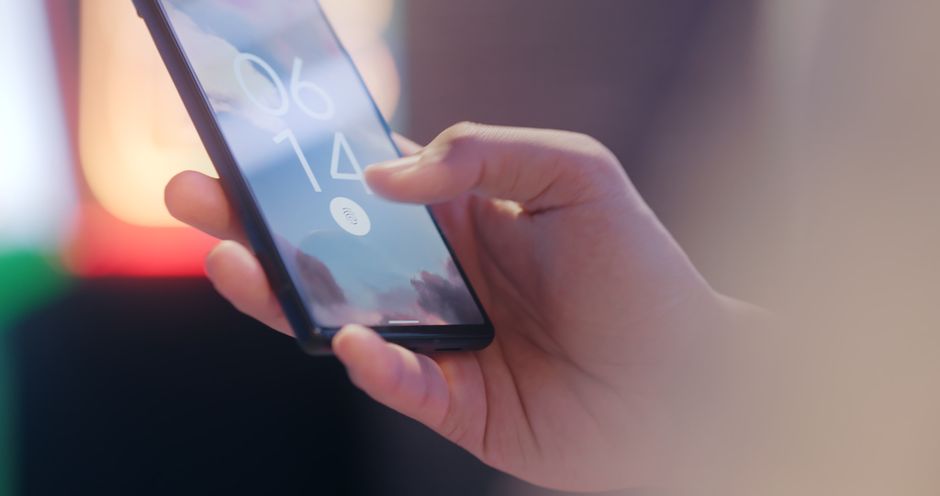 Närbild på en hand som håller en mobiltelefon låst med fingeravtryckssensor