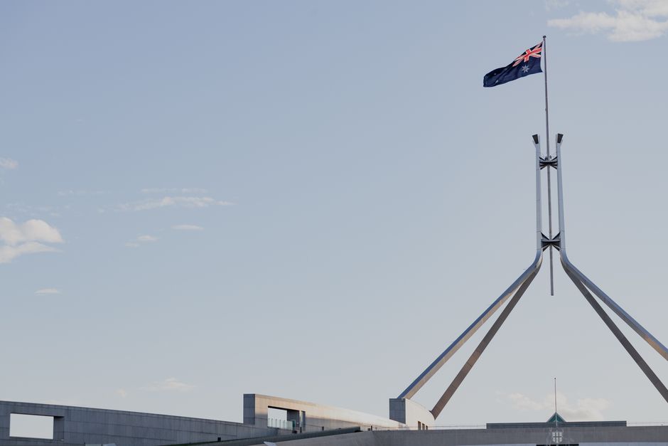 Australiens parlamentsbyggnad i Canberra med nationsflaggan mot blå himmel