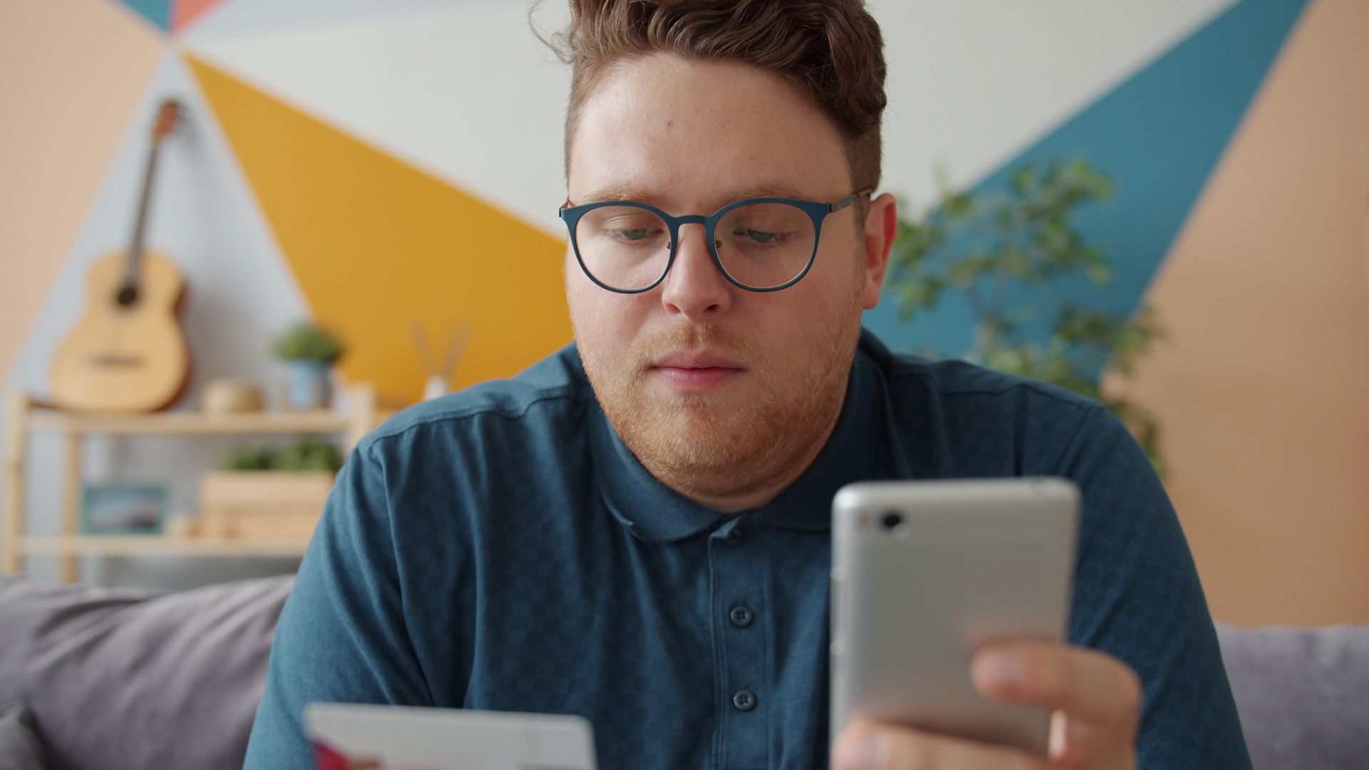 Man använder smartphone och kort för en mobil betalning hemma i vardagsrummet